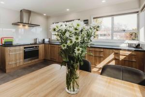 a vase of white flowers sitting on a table in a kitchen at Love It On Lemon - modern townhouse near CBD in New Plymouth