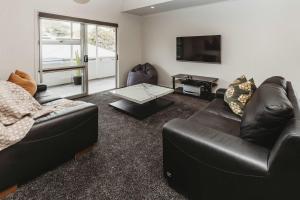 a living room with two leather couches and a tv at Love It On Lemon - modern townhouse near CBD in New Plymouth
