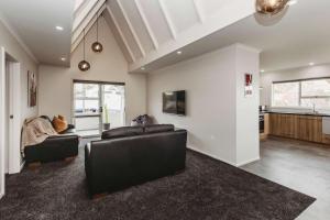 a living room with two leather couches and a kitchen at Love It On Lemon - modern townhouse near CBD in New Plymouth +13 photos