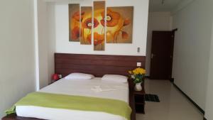 a bedroom with a bed and two paintings on the wall at The Den Guest House in Hikkaduwa