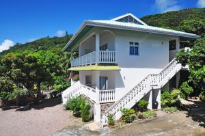 a white house with white stairs and a hill at Divers Lodge Guest House in Beau Vallon +36 photos