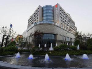 a building with a fountain in front of a building at Yang Peng Jin Jiang Hotel in Yangzhou