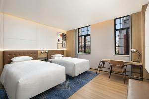 a hotel room with two beds and a desk at Four Points by Sheraton Tianjin Jiefang Bridge in Tianjin