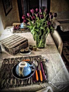 una mesa con un jarrón de flores púrpuras y un plato en B&B Monferrato La Casa Sui Tetti, en Murisengo