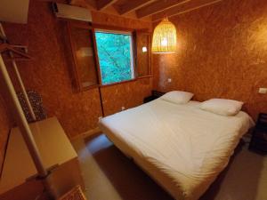 een kleine slaapkamer met een wit bed en een raam bij Gîte Chalet Morvan Bourgogne in Corancy +12 foto's