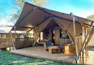 a tent with chairs and a table on a deck at Camping Le Val de Cesse in Mirepeisset