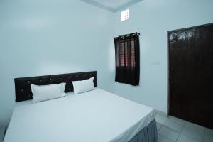 1 dormitorio con cama blanca y cabecero negro en Hotel O Shining Star, en Bhilai