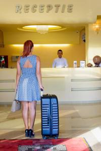 塞貝什的住宿－Hotel FAN Sebes，一位在商店里拿着手提箱站着的女人