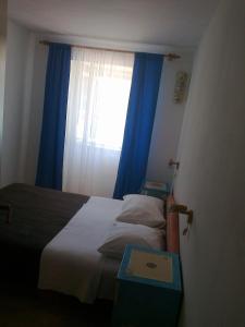 a bedroom with a bed and a window with blue curtains at Apartment Mira in Baška