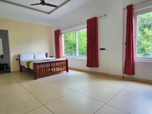 a bedroom with a bed and two windows at Misty Ville Homestay in Munnar