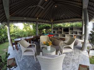 an outdoor patio with chairs and tables and a roof at The Horizon Hill Top Villa in Unawatuna