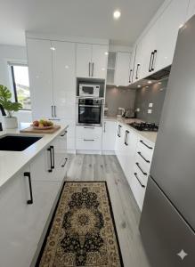 una cocina con armarios blancos y una alfombra en el suelo en Modern Family Home in Tawa - Wellington, en Wellington 4 fotos más