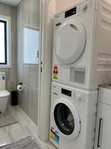 y baño con lavadora junto a un aseo. en Modern Family Home in Tawa - Wellington, en Wellington
