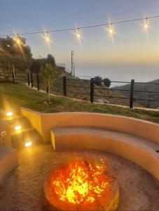 a fire pit in a yard with a view of the ocean at Là Guesthouses in ‘Aynţūrah