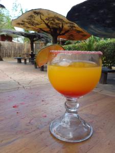 a glass of orange juice sitting on a table at Hotel Cabañas La Teca in Liberia