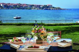 uma mesa com pratos de comida e copos de vinho em Selena Hotel em Sozopol