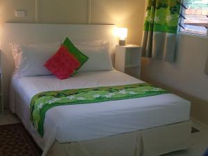 NgatangiiaにあるRei-Ris Placeの赤と緑の枕が置かれた白いベッド