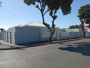 a white building with a tree next to a street at GRACE self-catering apartments in Goodwood