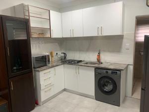a kitchen with white cabinets and a washing machine at GRACE self-catering apartments in Goodwood