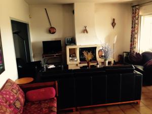 a living room with a black couch and a fireplace at Villa Ecluses Mediterranee in Portiragnes