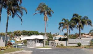 een straat met palmbomen voor een huis bij De Casa Leisuredene in Hibberdene