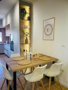 a dining room with a wooden table and white chairs at Gjirokastra Design Apartments in Gjirokastër