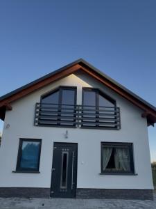 een wit huis met een balkon erbovenop bij Domek na Kaszubach u Doroty 