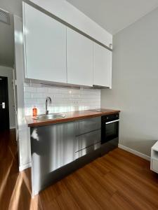 a kitchen with white cabinets and a stainless steel sink at Вид на закат, море и бассейн in Batumi