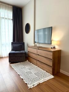 a living room with a flat screen tv and a chair at Вид на закат, море и бассейн in Batumi