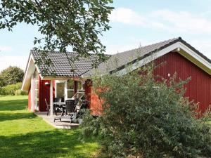 eine rote Scheune mit einem Tisch und Stühlen davor in der Unterkunft 5 star holiday home in Großenbrode in Großenbrode