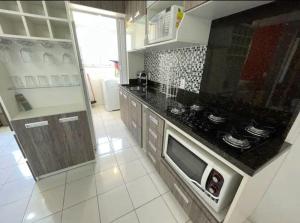 eine Küche mit Herd und Mikrowelle in der Unterkunft Hospedagem Apto Residencial Canela in Canela