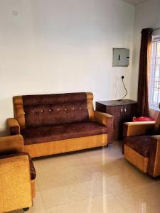 a living room with a brown couch and a table at Rooms with WiFi, Parking - 3BHK Villa in Kodaikānāl