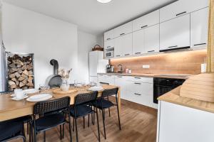 Una cocina con mesa y sillas y una cocina con gabinetes blancos. en Chalupa U přátel, en Kovářská