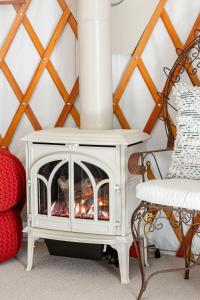 a white fireplace in a room next to a chair at Tranquil Yurt Rental for Two with Soothing Interior on Ranch near San Luis Obispo in Cayucos +33 photos