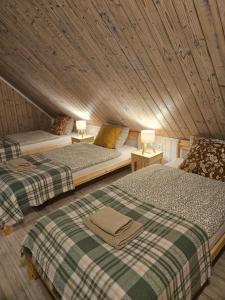 two beds in a room with a wooden ceiling at Ubytovanie Hronec in Hronec