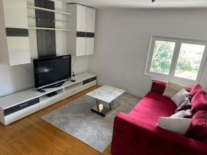 een woonkamer met een rode bank en een flatscreen-tv bij Chambres d'hôtes , Guest house in Chainaz-les-Frasses