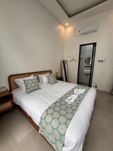 una camera da letto con un grande letto bianco con cuscini di Mai House Jogja a Piyungan