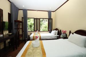 a hotel room with two beds and a television at We House River View Hotel And Travel in Luang Prabang