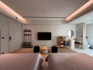 a bedroom with two beds and a table with chairs at Chuan Inn圈旅 站前館 in Tainan