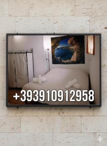 a mirror hanging on a wall with a bed at Room Calafatari in Siracusa