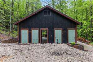a black barn with four doors and a pile of gravel at A-Frames Under the Canopy - Multi-Cabin Retreat in Rogers