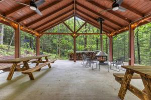 a pavilion with wooden tables and chairs in the woods at A-Frames Under the Canopy - Multi-Cabin Retreat in Rogers