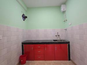 a red kitchen with a sink and red cabinets at Aangan Royal Stay in Dharmsala +22 photos