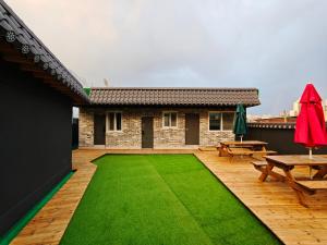 a backyard with a green lawn and picnic tables at Unit D Hostel in Seoul