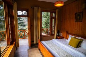 a bedroom with a bed and two windows at Doghari Chalets Jibhi by Himtrek Stays in Jibhi