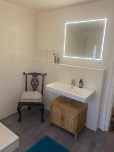 a bathroom with a sink and a chair and a mirror at Gästewohnung Augsburg - Spickel in Augsburg +2 photos