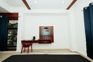 a room with a bed and a tv on a wall at Falnir Palace in Mangalore