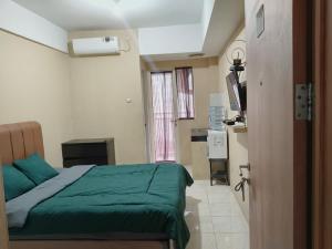 a bedroom with a green bed and a kitchen at Bram Rooms Green Lake View Ciputat in Pondokcabe Hilir