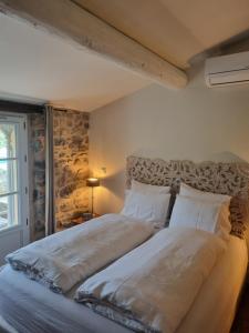 a large bed in a bedroom with a stone wall at Mas Tulipe de Soie in Bevons