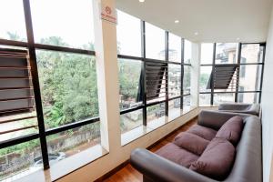 a living room with a couch and large windows at Falnir Palace in Mangalore